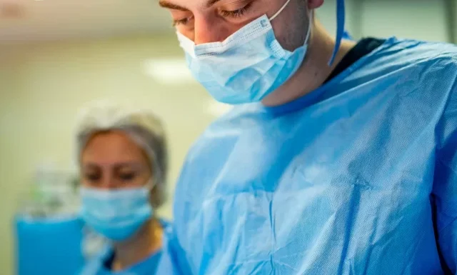 portrait-doctor-medical-specialist-vertical-portrait-man-scrubs-light-background-with-operating-room-closeup